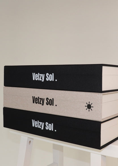 Stack of books with 'Vezy Sol' branding on a white surface